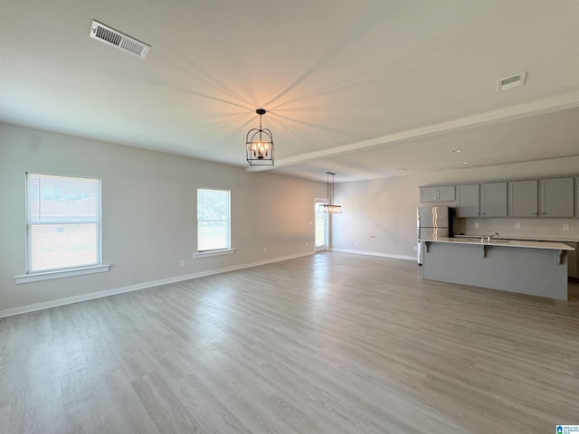 115 Ridgeview Cir, Jemison, AL 35085 - unfurnished living room with a chandelier, light wood-type flooring, baseboards, and a sink