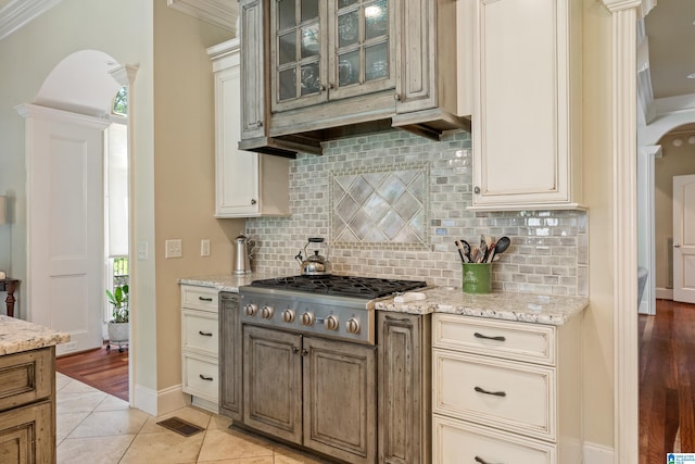 1272 Highland Lakes Trl, Birmingham, AL 35242 - kitchen with stainless steel gas cooktop, arched walkways, cream cabinetry, backsplash, and ornamental molding