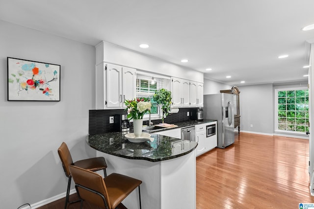 2013 Crossvine Rd, Hoover, AL 35244 - kitchen with stainless steel appliances, white cabinetry, decorative backsplash, a sink, and a peninsula