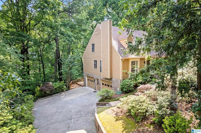 2013 Crossvine Rd, Hoover, AL 35244 - view of front facade featuring an attached garage, driveway, stone siding, and a chimney