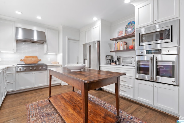 409 Euclid Ave, Mountain Brook, AL 35213 - kitchen with appliances with stainless steel finishes, wall chimney range hood, dark wood-style floors, backsplash, and light countertops