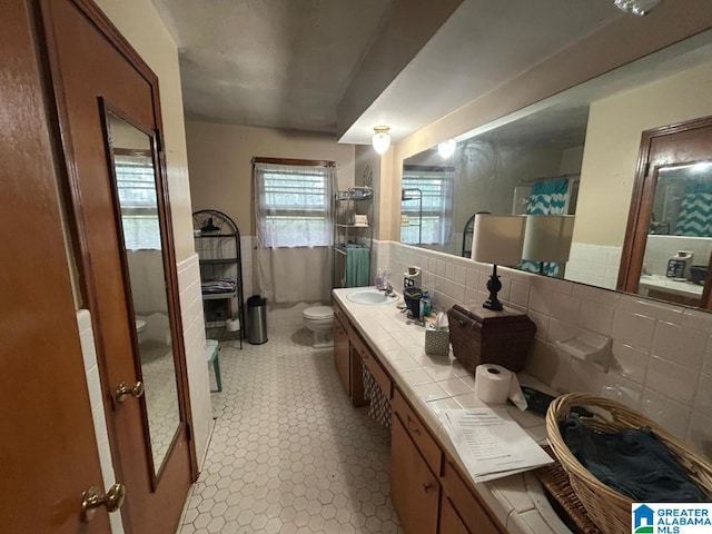 409 Morningview St, Athens, AL 35611 - bathroom with toilet, tile walls, double vanity, a shower, and wainscoting