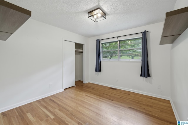222 Patricia Rd, Madison, AL 35758 - unfurnished bedroom featuring light wood-style floors, a textured ceiling, baseboards, and a closet
