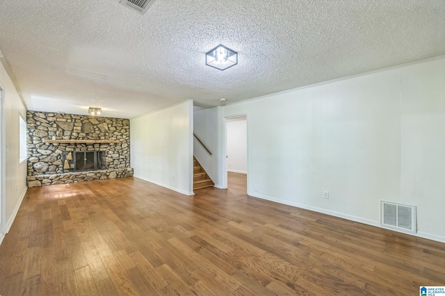 222 Patricia Rd, Madison, AL 35758 - unfurnished living room with stairway, a textured ceiling, wood finished floors, a stone fireplace, and baseboards