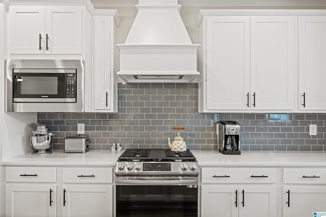 173 Atlantic Ln, Birmingham, AL 35242 - kitchen with stainless steel appliances, custom exhaust hood, light countertops, white cabinets, and decorative backsplash