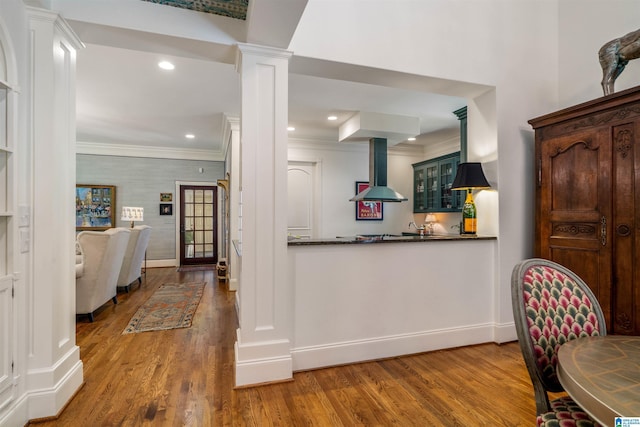 3242 Country Club Rd, Mountain Brook, AL 35213 - kitchen featuring wall chimney exhaust hood, ornate columns, wood finished floors, dark countertops, and ornamental molding