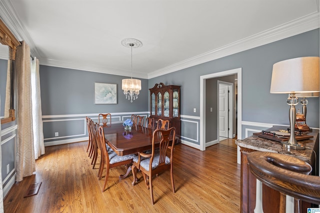 4063 Milners Cres, Hoover, AL 35242 - dining space with wood finished floors, ornamental molding, a chandelier, and a wainscoted wall