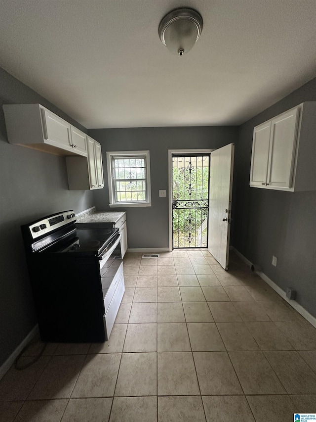 118 3rd Ave SW, Birmingham, AL 35211 - kitchen featuring stainless steel electric range oven, baseboards, light tile patterned floors, white cabinetry, and light countertops