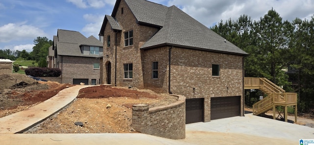 1077 Grande View Pass, Alabaster, AL 35114 - view of side of home featuring a garage, stairway, brick siding, driveway, and roof with shingles