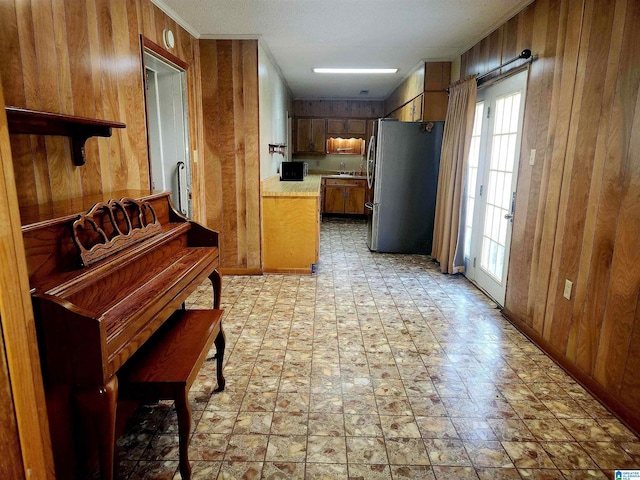 5810 Stemley Bridge Rd, Talladega, AL 35160 - kitchen featuring freestanding refrigerator, wooden walls, light countertops, a sink, and brown cabinets