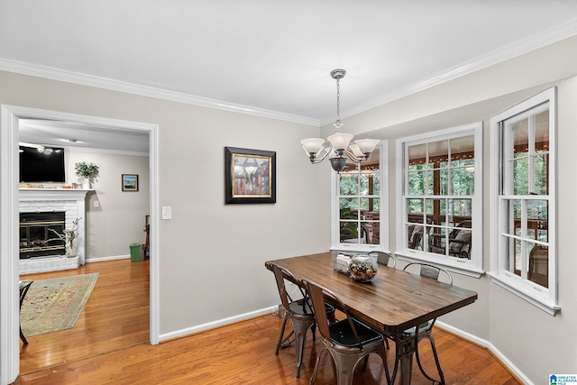 545 Russet Bend Dr, Hoover, AL 35244 - dining area with ornamental molding, baseboards, light wood-type flooring, a chandelier, and a stone fireplace