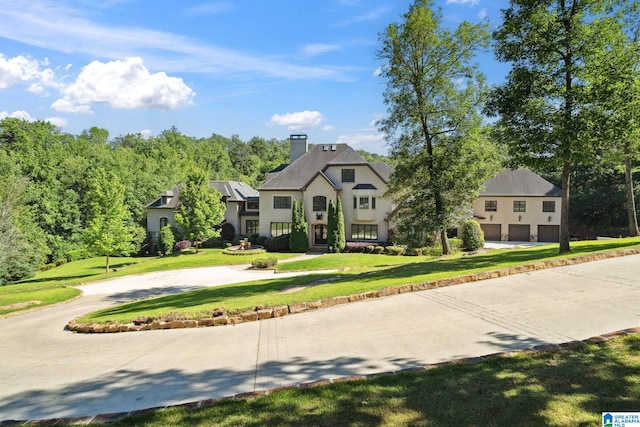 2821 Shook Hill Cir, Mountain Brook, AL 35223 - view of front of property featuring a chimney, curved driveway, a front lawn, stucco siding, and a garage