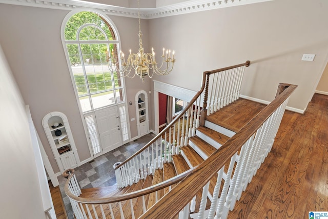2100 Southwinds Cir, Hoover, AL 35244 - stairs with a towering ceiling, built in shelves, a chandelier, wood finished floors, and baseboards