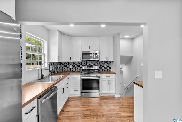 1712 34th Pl N, Birmingham, AL 35234 - kitchen with appliances with stainless steel finishes, butcher block countertops, a sink, light wood finished floors, and decorative backsplash