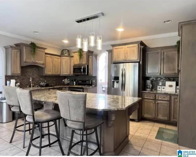 5616 Elliott Cir, Mccalla, AL 35111 - kitchen with appliances with stainless steel finishes, light stone countertops, backsplash, a kitchen island, and a kitchen breakfast bar
