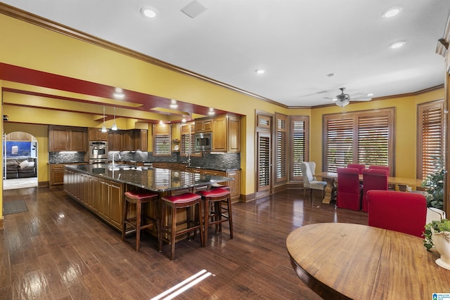 200 Asphodel Dr, Dothan, AL 36303 - kitchen featuring appliances with stainless steel finishes, ornamental molding, a large island, a kitchen bar, and backsplash
