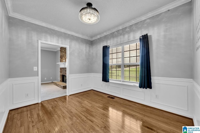 200 Shady Point Rd, Locust Fork, AL 35097 - spare room featuring a wainscoted wall, wood finished floors, a chandelier, a stone fireplace, and ornamental molding