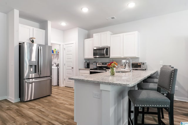 119 Polo Downs, Chelsea, AL 35043 - kitchen with appliances with stainless steel finishes, a peninsula, light wood-style floors, a kitchen bar, and white cabinets