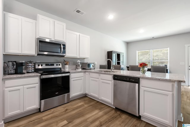 119 Polo Downs, Chelsea, AL 35043 - kitchen with appliances with stainless steel finishes, a sink, a peninsula, light wood-type flooring, and white cabinetry