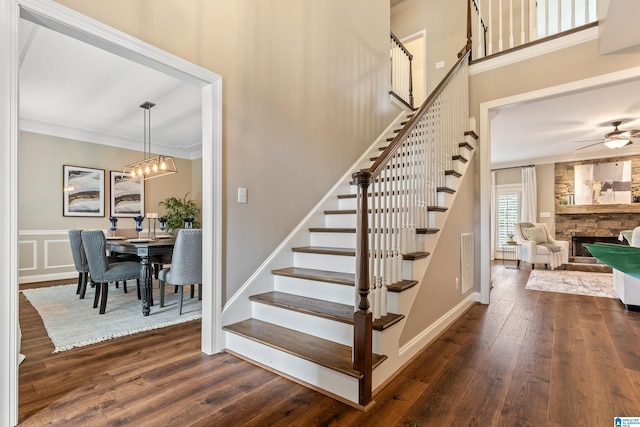 5265 Lake Crest Cir, Hoover, AL 35226 - staircase with wood finished floors, crown molding, a ceiling fan, a fireplace, and a chandelier