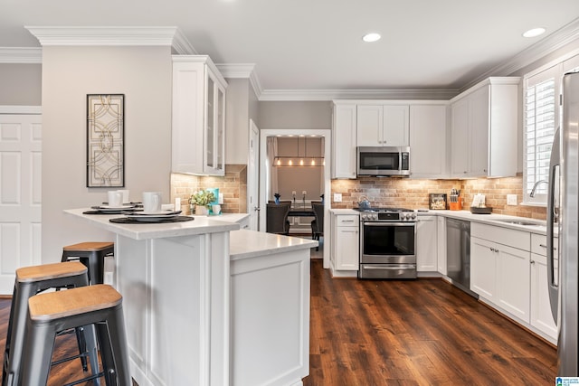 5265 Lake Crest Cir, Hoover, AL 35226 - kitchen with stainless steel appliances, ornamental molding, light countertops, a breakfast bar, and dark wood-style floors