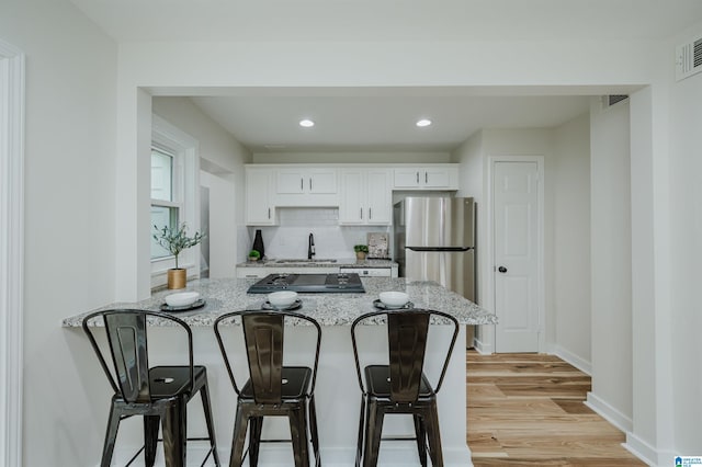 1751 Valley Ave Unit D, Homewood, AL 35209 - kitchen featuring freestanding refrigerator, a sink, a kitchen breakfast bar, white cabinetry, and recessed lighting