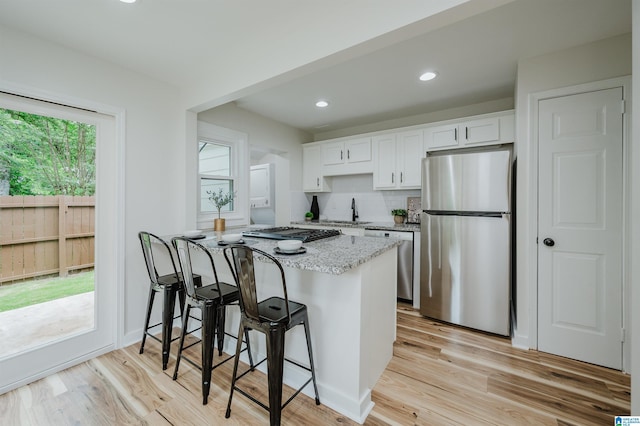 1751 Valley Ave Unit D, Homewood, AL 35209 - kitchen featuring appliances with stainless steel finishes, a sink, a breakfast bar, white cabinetry, and light stone countertops
