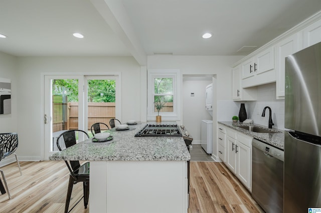 1751 Valley Ave Unit D, Homewood, AL 35209 - kitchen with appliances with stainless steel finishes, a sink, stacked washing machine and dryer, a center island, and a kitchen breakfast bar