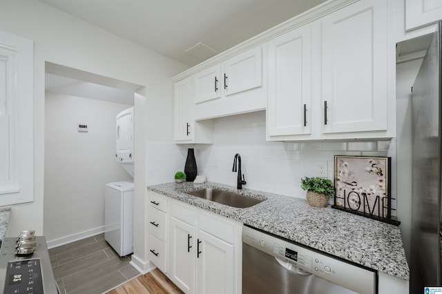 1751 Valley Ave Unit D, Homewood, AL 35209 - kitchen with appliances with stainless steel finishes, a sink, stacked washing machine and dryer, tasteful backsplash, and light wood-type flooring