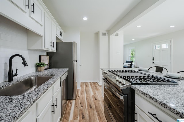1751 Valley Ave Unit D, Homewood, AL 35209 - kitchen with stainless steel appliances, a sink, light wood-style floors, light stone countertops, and backsplash