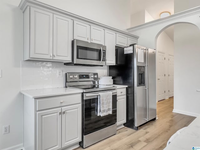 156 Brook Highland Cv, Birmingham, AL 35242 - kitchen with stainless steel appliances, arched walkways, light countertops, backsplash, and light wood finished floors