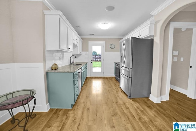 123 Whitestone Trl, Calera, AL 35040 - kitchen featuring appliances with stainless steel finishes, a sink, arched walkways, white cabinetry, and light wood-style floors