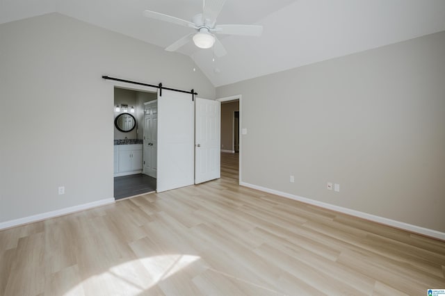 2019 Russet Meadows Ct, Helena, AL 35244 - unfurnished bedroom featuring lofted ceiling, a barn door, baseboards, light wood-type flooring, and connected bathroom