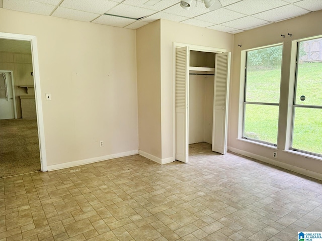 1315 Gloria Ln, Weaver, AL 36277 - unfurnished bedroom featuring a paneled ceiling, baseboards, light stone finish flooring, and a closet