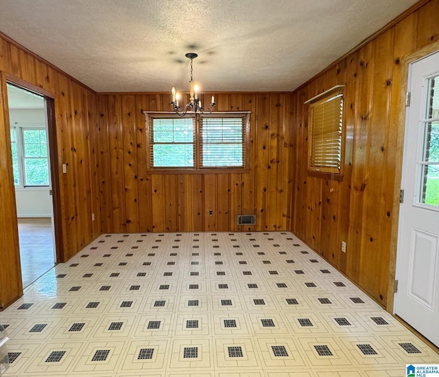 1315 Gloria Ln, Weaver, AL 36277 - unfurnished dining area featuring a chandelier, a textured ceiling, and wooden walls