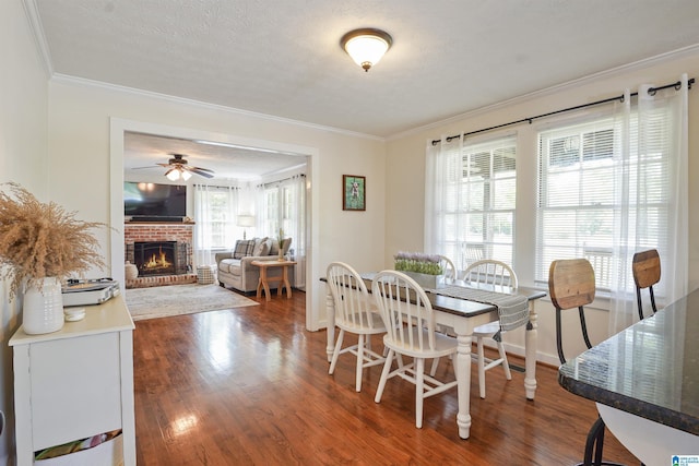 1693 4th Ave N, Clanton, AL 35045 - dining area featuring ornamental molding, dark wood-type flooring, a brick fireplace, ceiling fan, and baseboards