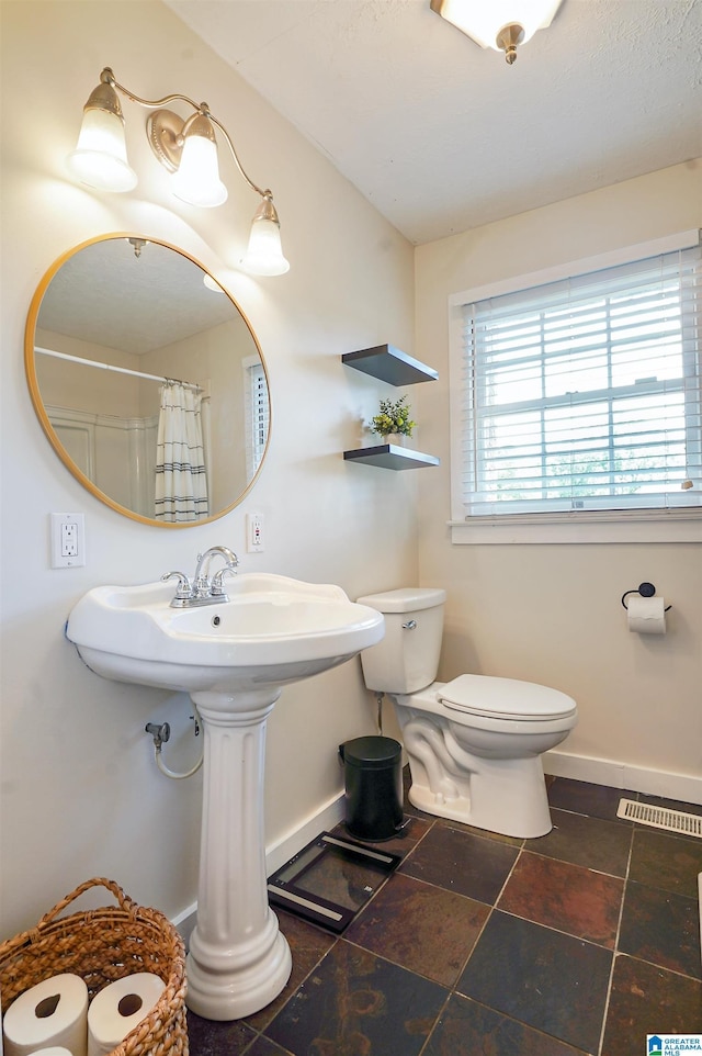 1693 4th Ave N, Clanton, AL 35045 - bathroom featuring baseboards, toilet, and curtained shower