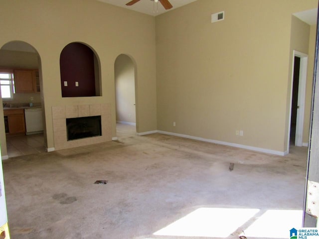 221 High Ridge Dr, Pelham, AL 35124 - unfurnished living room featuring ceiling fan, light colored carpet, a tile fireplace, arched walkways, and baseboards