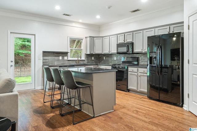 1033 Inverness Cove Way, Hoover, AL 35242 - kitchen with black appliances, gray cabinetry, a breakfast bar area, ornamental molding, and recessed lighting