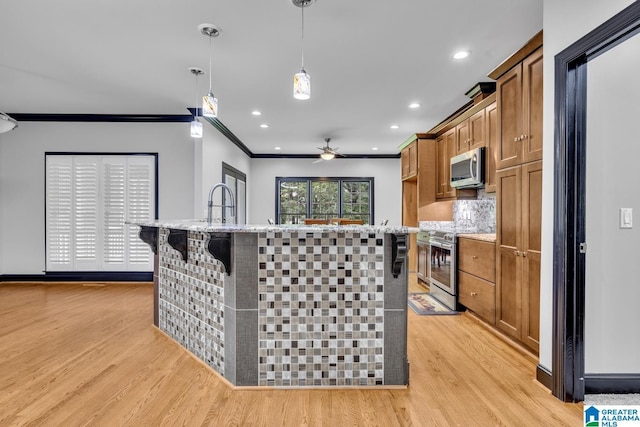 1700 Leisure Ln NW, Cullman, AL 35055 - kitchen with appliances with stainless steel finishes, light wood-style flooring, ornamental molding, brown cabinets, and a center island with sink