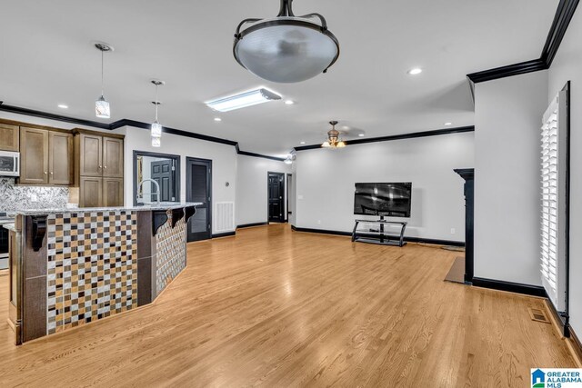 1700 Leisure Ln NW, Cullman, AL 35055 - kitchen with crown molding, light wood-type flooring, an island with sink, decorative backsplash, and decorative light fixtures