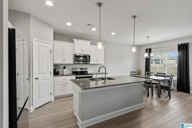 27281 Mckenna Dr, Athens, AL 35613 - kitchen featuring appliances with stainless steel finishes, a sink, light wood-style flooring, dark stone counters, and white cabinetry