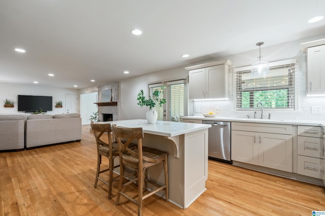 1355 Starcross Dr, Vestavia Hills, AL 35216 - kitchen featuring stainless steel dishwasher, a sink, a fireplace, decorative backsplash, and light wood finished floors