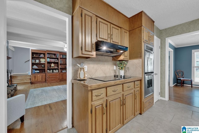 3258 Tyrol Ln, Vestavia Hills, AL 35216 - kitchen with under cabinet range hood, double oven, black electric cooktop, light countertops, and decorative backsplash