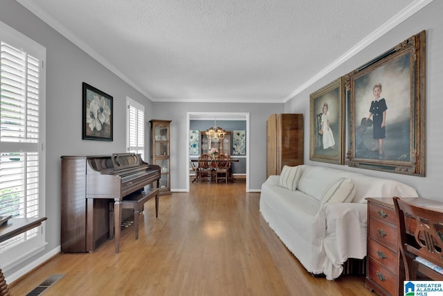 3258 Tyrol Ln, Vestavia Hills, AL 35216 - living room featuring a chandelier, a textured ceiling, light wood-style flooring, ornamental molding, and baseboards