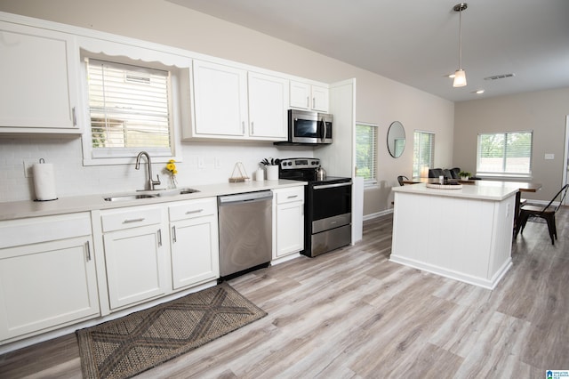 539 63rd St S, Birmingham, AL 35212 - kitchen with appliances with stainless steel finishes, a sink, light wood-style flooring, tasteful backsplash, and white cabinetry