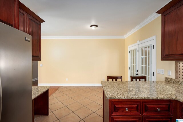 101 Mill Rd, Springville, AL 35146 - kitchen with freestanding refrigerator, ornamental molding, reddish brown cabinets, light tile patterned floors, and a peninsula