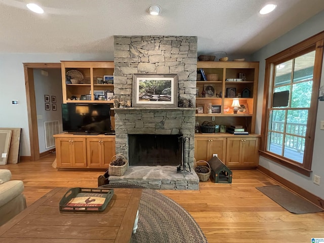 720 Good Hope Delta Rd, Delta, AL 36258 - living area featuring baseboards, light wood finished floors, a stone fireplace, and a textured ceiling
