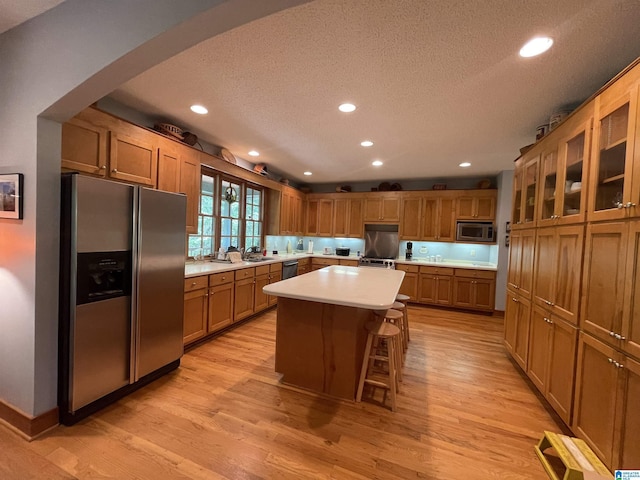 720 Good Hope Delta Rd, Delta, AL 36258 - kitchen featuring appliances with stainless steel finishes, a textured ceiling, arched walkways, light countertops, and light wood finished floors