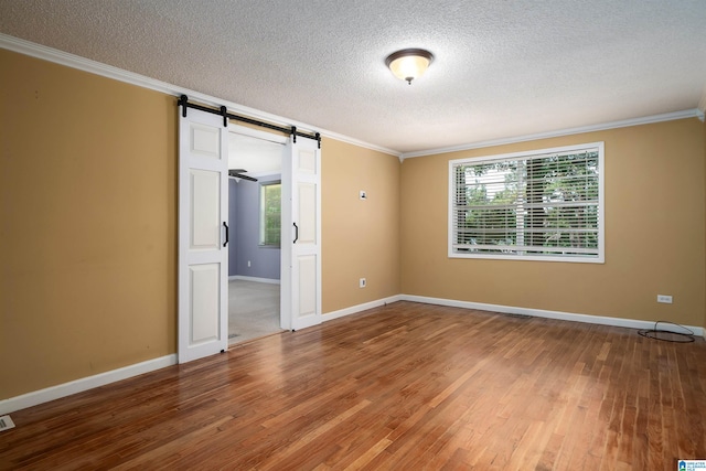 220 Honeysuckle Ln, Gardendale, AL 35071 - unfurnished room featuring a textured ceiling, crown molding, a barn door, wood finished floors, and baseboards